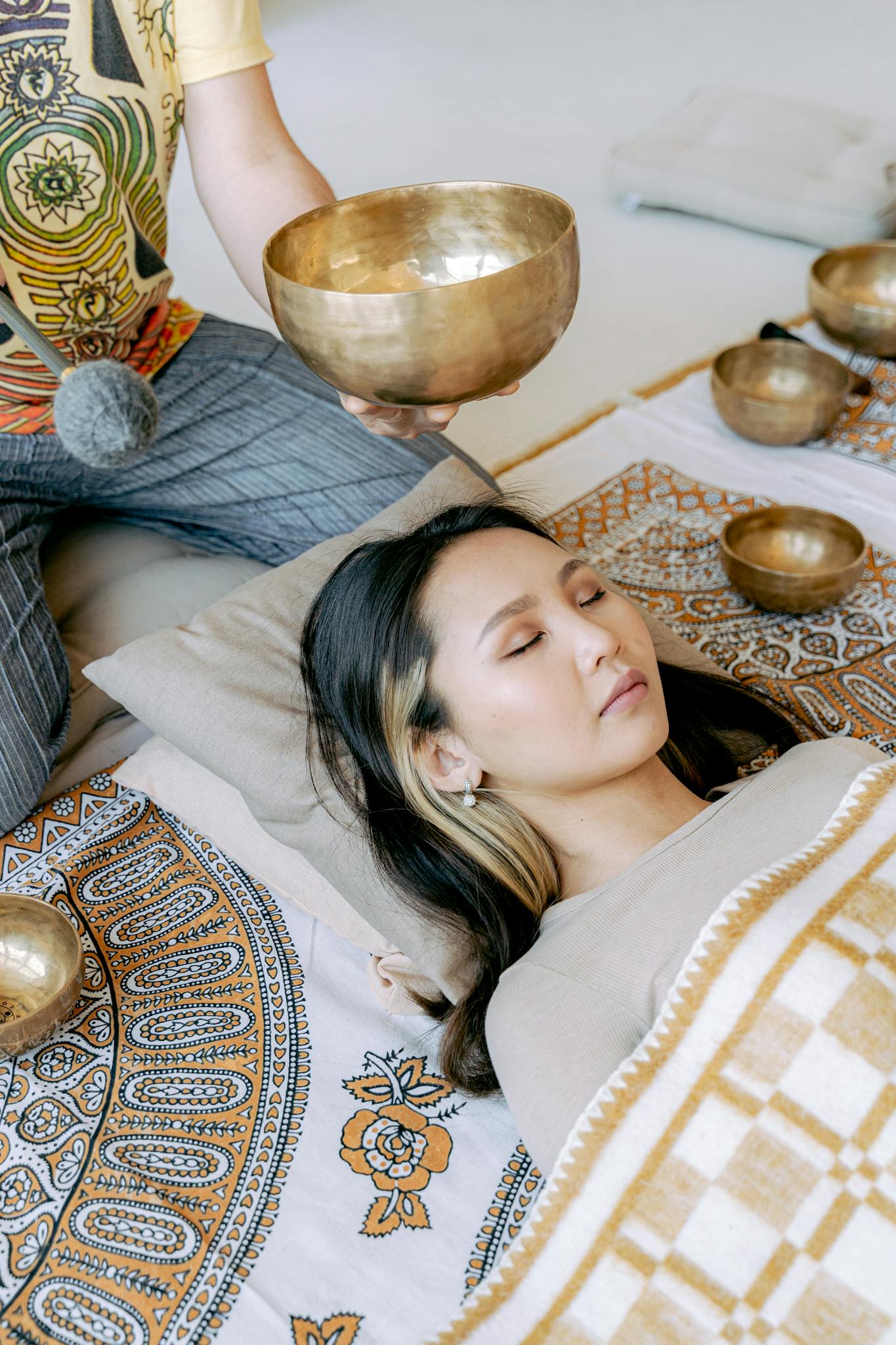 A woman peacefully undergoes Tibetan singing bowl therapy, promoting relaxation and meditation.